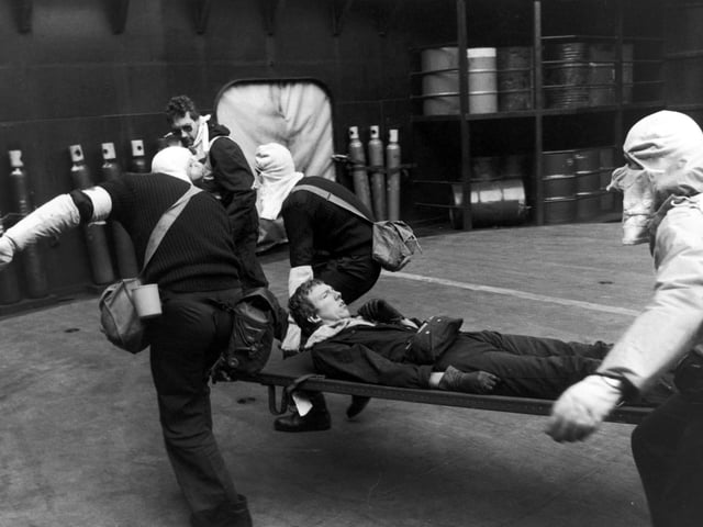 A survivor from the Exocet missile attack on HMS Sheffield is aided by men wearing anti-flash hoods on board HMS Hermes after being lifted to the ship by helicopter, 4th May 1982. Twenty sailors lost their lives in the incident. (Photo by Martin Cleaver/Pool/Getty Images)
