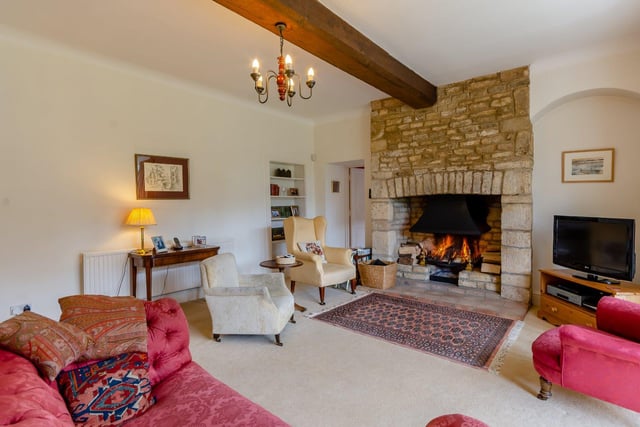 The snug living room is one of five reception rooms and boasts an impressive stone fireplace at its heart, providing a cosy place to relax.