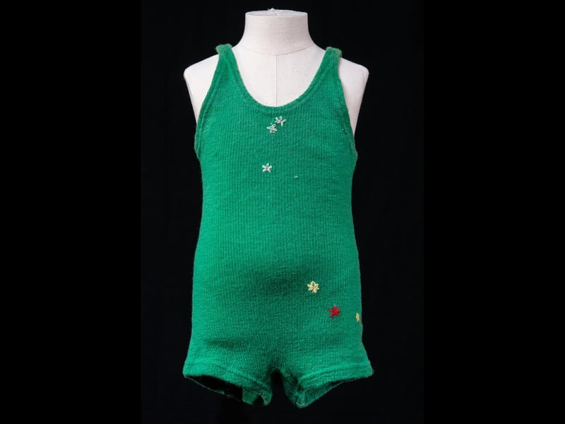 This swimsuit belonged to Mabel Macaulay who grew up on Kirkibost Island off the south west coast of North Uist. It was made by her mother or aunt on a machine, like many of her clothes, and repaired by hand with holes stitched together with little embroidered flowers.
