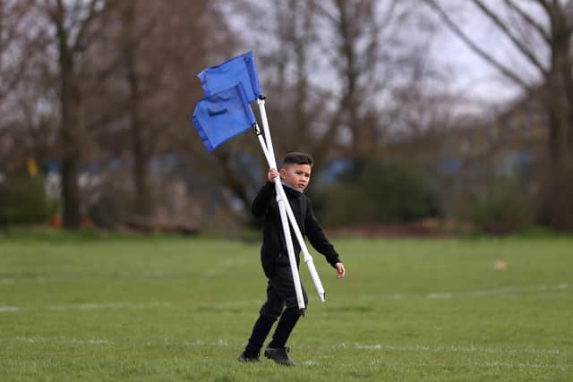 A young boy collects the corner flags (Photo by Alex Pantling/Getty Images)