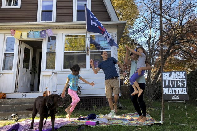 From left, 7-year-old Nina, her father Greg Healey and Julia Healy dance with 5-year-old Liza Healy, and dog is Stella as cars pass by honking horns in celebration after former vice president and Democratic presidential candidate Joe Biden was announced as the winner. (AP Photo/Mark Lennihan)