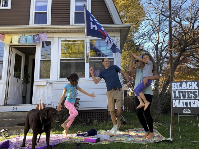 From left, 7-year-old Nina, her father Greg Healey and Julia Healy dance with 5-year-old Liza Healy, and dog is Stella as cars pass by honking horns in celebration after former vice president and Democratic presidential candidate Joe Biden was announced as the winner. (AP Photo/Mark Lennihan)
