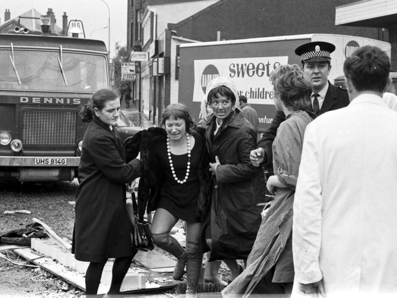 A distressed woman is helped from the scene at Clarkston Toll in Glasgow, after a faulty gas main exploded killing 20 shoppers and injuring hundreds in October 1971.