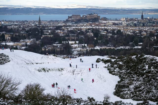 A view of Edinburgh Castle from The Braids with people sledging in the snow