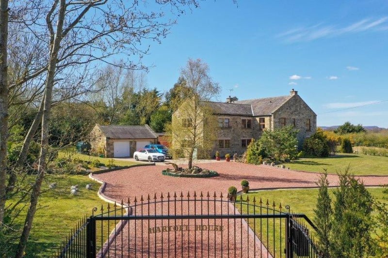 Electronic gated entrance onto a large gravelled driveway with ample parking for multiple vehicles.