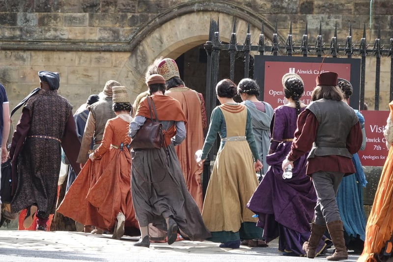 Extras in medieval costume head into Alnwick Castle.