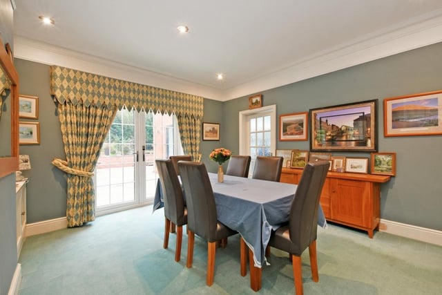 The dining room enjoys natural light from the French doors opening onto the grounds.