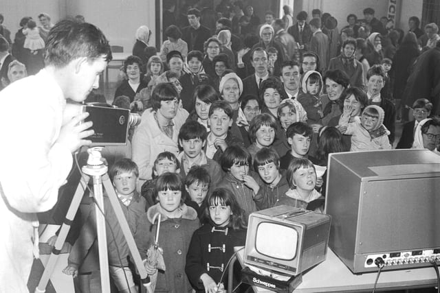 The crowd see themselves on TV as they are filmed at the May Fair in Pilton in 1966.