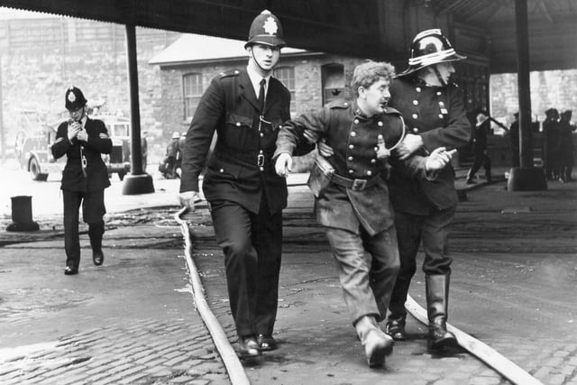 An injured fireman is helped to safety after the devastating fire at the Wicker Goods Yard in July 1966