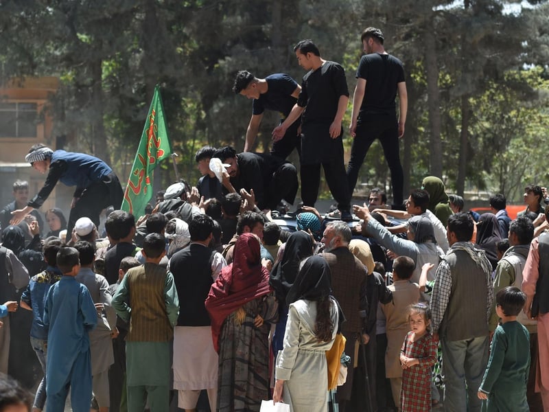 Internally displaced Afghan people, who fled from the northern province due to battle between Taliban and Afghan security forces, gather to receive free food
