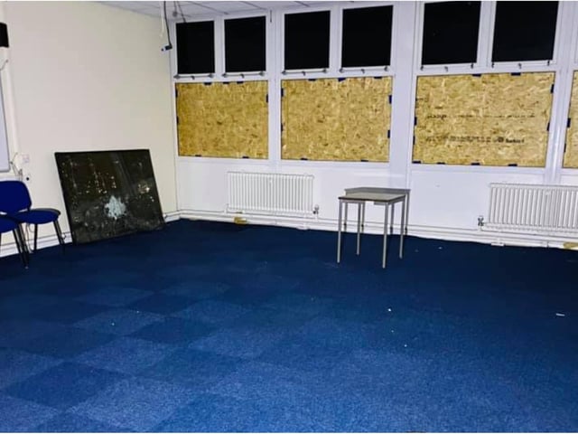 Windows have been boarded up but classroom furniture remains.