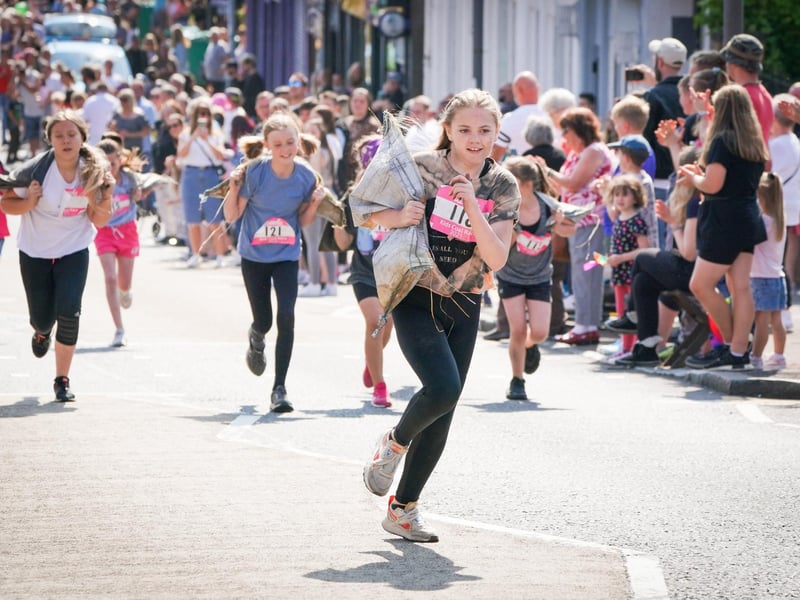 Competitors in the Junior Race take part in the Scottish Coal Carrying Championships through the streets of Kelty in Fife.  Picture date: Saturday August 28, 2021. PA Photo. The annual event is one of only two Coal Races in the world and the men's race requires participants to carry a 50-kilo bag of coal and the women's race requires a 25-kilo bag of coal to be carried over 1000 metres through the village. Photo credit should read: Jane Barlow/PA Wire 