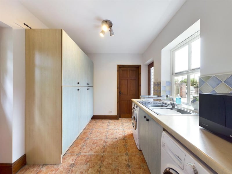 Utility Room with exterior door to the front elevation, a range of fitted units with complementary work-surface, inset sink with mixer tap, plumbing for automatic washing machine, timber framed part glazed stable door opening onto the rear courtyard.