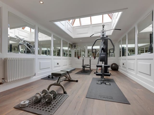This well-proportioned at-home gym provides plenty of space for several pieces of workout equipment, and includes mirrored walls, data points and a built-in surround sound system.