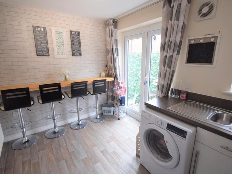 Breakfast kitchen has a range of modern high gloss units with contrasting worktops including stainless steel oven and hob with chimney style hood over, stainless steel sink with mixer tap and drainer, plumbing for a washing machine, space for fridge freezer, concealed Ideal Logic combi gas boiler, UPVC double glazed window, breakfast bar and UPVC double glazed patio doors.