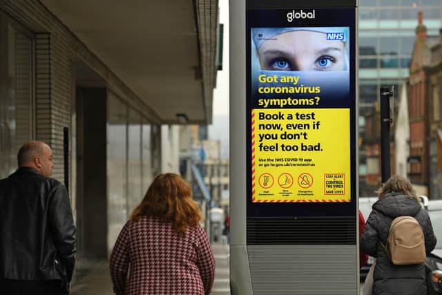 Pepple walk past a display featuring health advice in the shopping district in central Sheffield (Photo by Oli SCARFF / AFP) (Photo by OLI SCARFF/AFP via Getty Images)