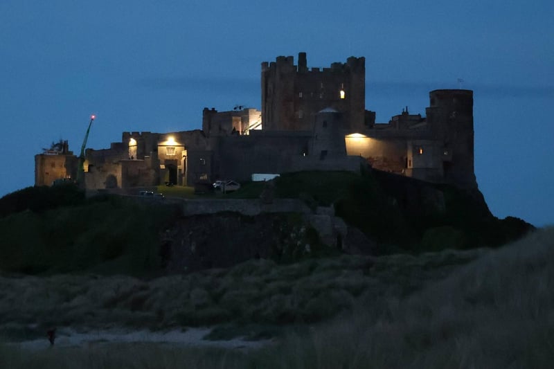 Bamburgh Castle lit up in the night sky.