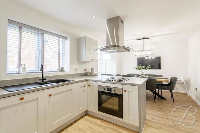 The kitchen from a different angle, showing its gorgeous fixtures and fittings. It also boasts an integrated dishwasher and fridge freezer, plus spotlights, laminate flooring, a central-heating radiator and windows to the back of the property.