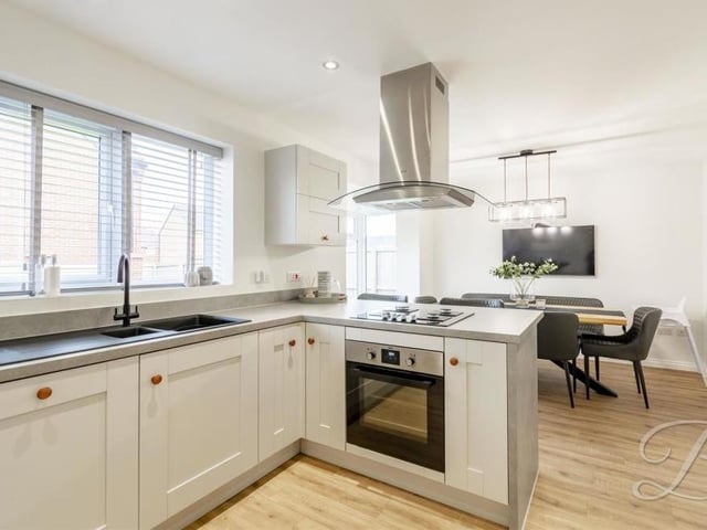 The kitchen from a different angle, showing its gorgeous fixtures and fittings. It also boasts an integrated dishwasher and fridge freezer, plus spotlights, laminate flooring, a central-heating radiator and windows to the back of the property.
