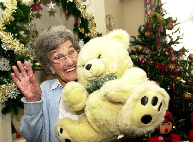 Bertha Partridge, aged 83 holding a large teddy bear at the annual Christmas Fayre held at the Woodlea Residential Home. 2003.