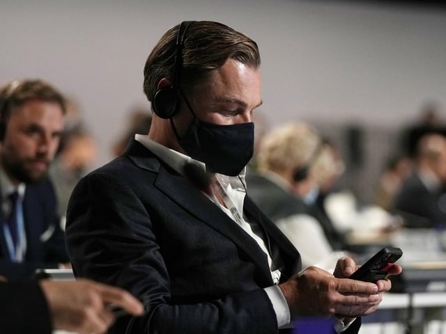 DiCaprio looked at a mobile phone as he attended a panel discussion.