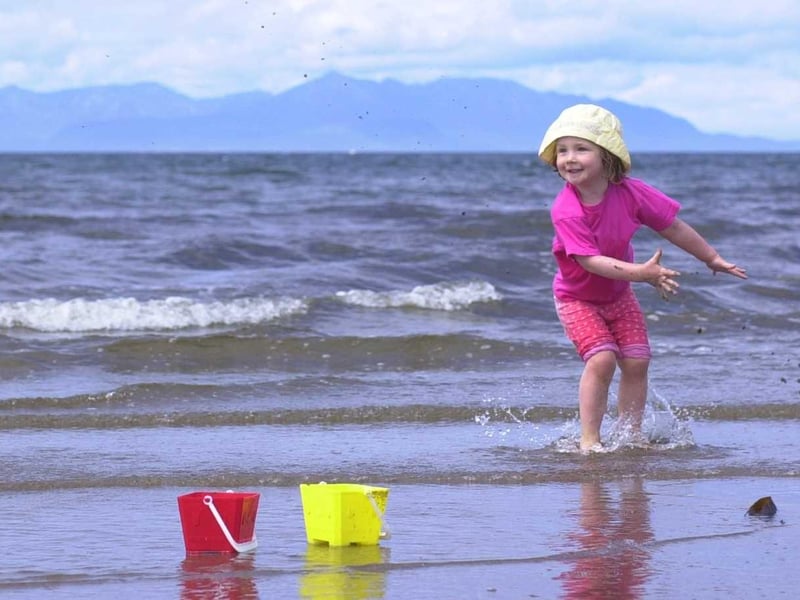 Ayr beach on the first week of Glasgow Fair Fortnight in 2000, with three-year-old Jade Henderson of Robroyston splashing in the Firth of Clyde with the Isle of Arran in the background.