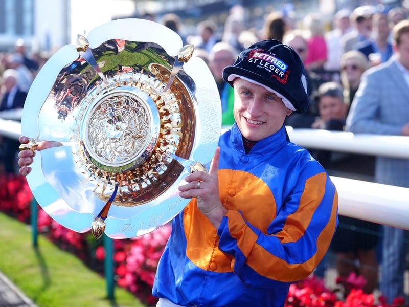 Jockey Tom Marquand celebrates with a trophy after victory in the Betfred St Leger Stake with horse Scandinavia at Doncaster.