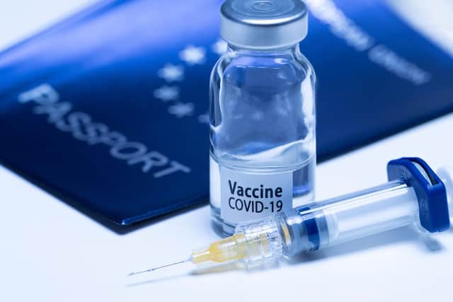 A picture taken on March 3, 2021 in Paris shows a vaccine vial reading "Covid-19 vaccine" and a syringe next to an European passport. (Photo by JOEL SAGET / AFP) (Photo by JOEL SAGET/AFP via Getty Images)
