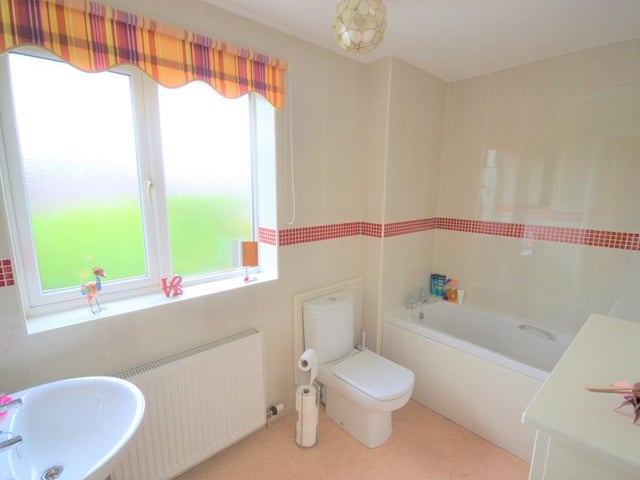 Family bathroom - A contemporary family bathroom having a three piece suite finished in white incorporating a bath with shower over and screen, wash basin with chrome fittings, low level flush wc, central heating radiator, shaving socket, UPVC double glazed obscure window, airing cupboard with shelving and complimented with ceramic wall tiles.