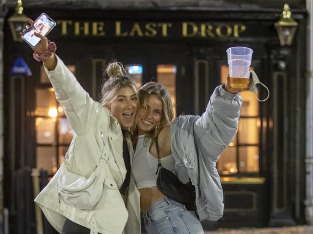 Friends gather outside The Last Drop in Edinburgh to make the most of pubs while they remain open.