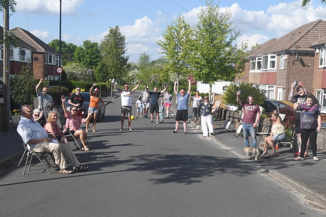 Residents of June Road in Woodhouse celebrate the seventy-fifth anniversary of VE Day with a drink and a cheer while maintaining a two-metre distance between households.
