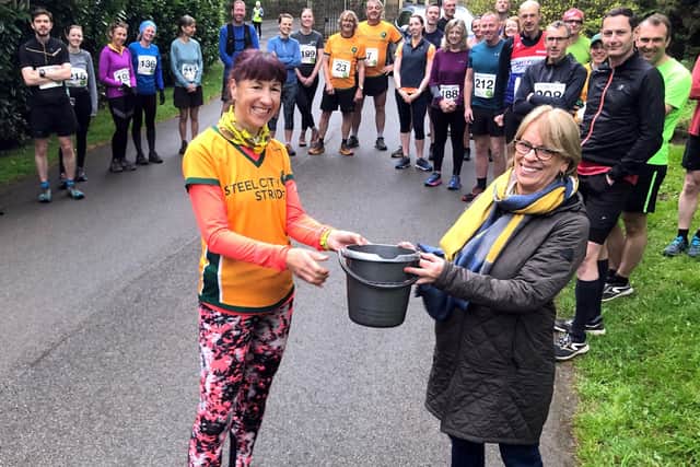 Kate Scott of Steel City Striders handing over the latest collection in the Steel City Trail 10 'conservation donation bucket' to Maggie Girling of the Friends of Whirowbrook Park 