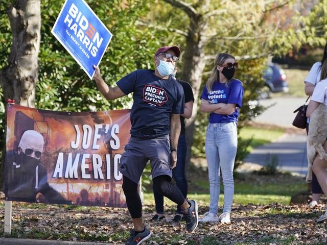 Supporters of President-elect Joe Biden wave signs and jumps up and down at the entrance to Trump National golf club in Sterling, Va (AP Photo/Steve Helber)