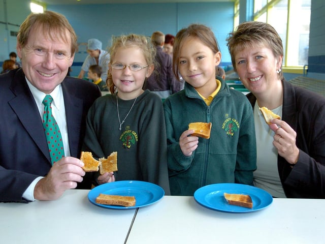 Southey Green Juniors headteacher Jim Fryer, with pupils Holly Stancill, 7, and Hayley Stuart, 8, and Councillor Angela Smith, cabinet member for education, tucking into food at the school's new breakfast club in October 2004