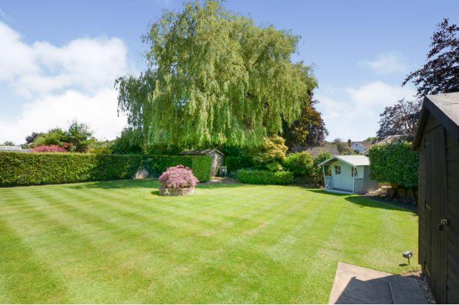 The back garden is mainly lawn and has mature trees and bushes. There are two sheds and there is a store which has a side door, electric heating and sockets.