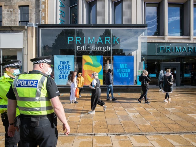 People queue at a safe distance from each other while officers look on.