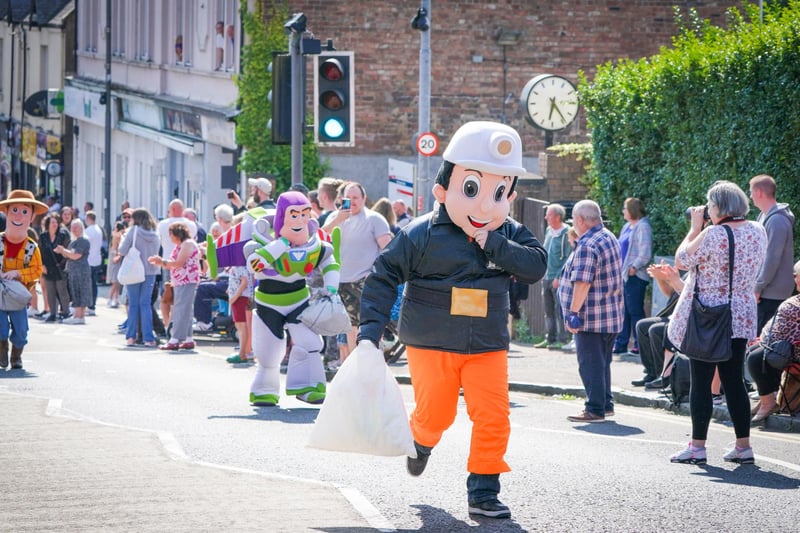 Competitors in the Mascot Race take part in the Scottish Coal Carrying Championships through the streets of Kelty in Fife.  Picture date: Saturday August 28, 2021. PA Photo. The annual event is one of only two Coal Races in the world and the men's race requires participants to carry a 50-kilo bag of coal and the women's race requires a 25-kilo bag of coal to be carried over 1000 metres through the village. Photo credit should read: Jane Barlow/PA Wire 