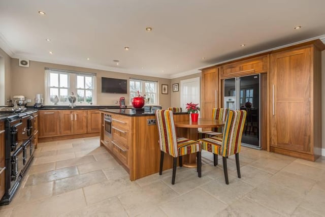 The description adds: "The spacious kitchen provides a full range of wall and base units and central island with granite worktops, Aga oven and a range of modern integrated appliances."