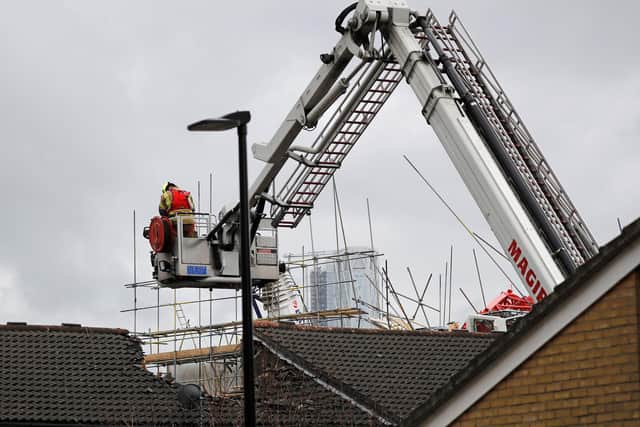 Members of the Fire Brigade stand on a platform as they look into the damaged roof of a property in Bow, east London on July 8, 2020, after a crane collapsed onto flats under construction.