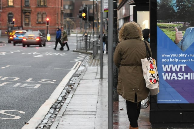 A shopper waits for a bus to arrive in Victoria Road.