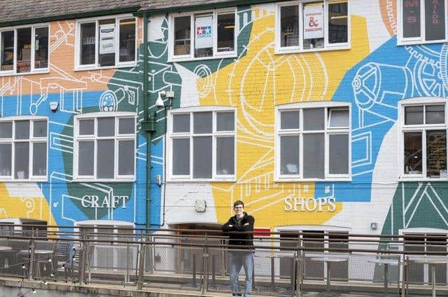 Will Rea next to his Workings of Sheffield mural on the public wall overlooking the courtyard in Orchard Square