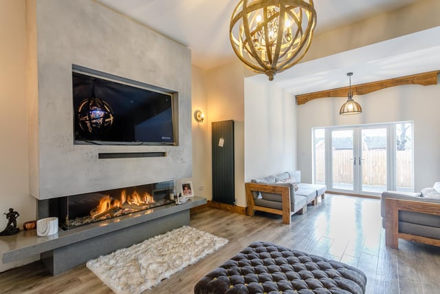 The "impressive" living room, benefits from a large modern glass fireplace, modern wall mounted radiators, high ceilings and large French doors that allow natural light to flood the room.