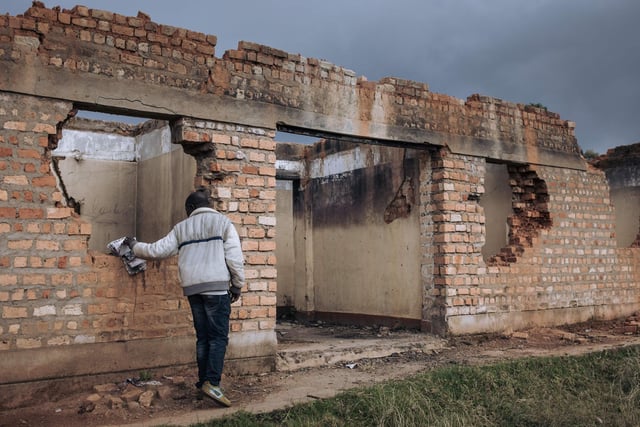 A civilian staff member of the United Nations Organization Stabilization Mission in the Democratic Republic of the Congo (MONUSCO) inspects the ruins of the Bijombo health center destroyed by armed men.