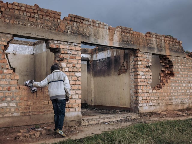 A civilian staff member of the United Nations Organization Stabilization Mission in the Democratic Republic of the Congo (MONUSCO) inspects the ruins of the Bijombo health center destroyed by armed men.