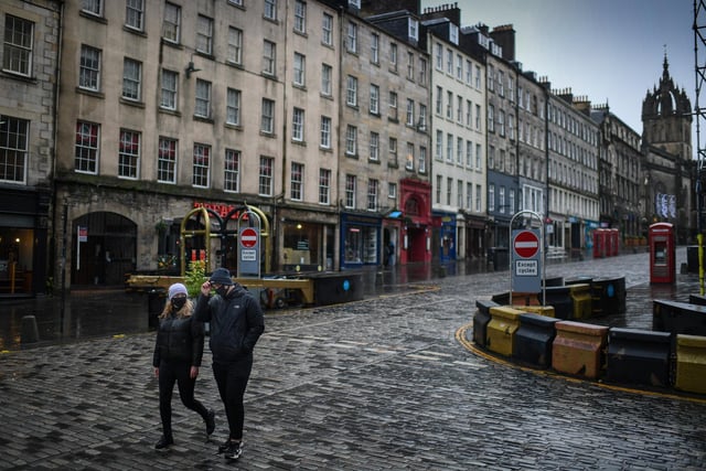 Members of the public walk through a deserted Edinburgh City Centre on January 4, 2021 in Edinburgh, Scotland.