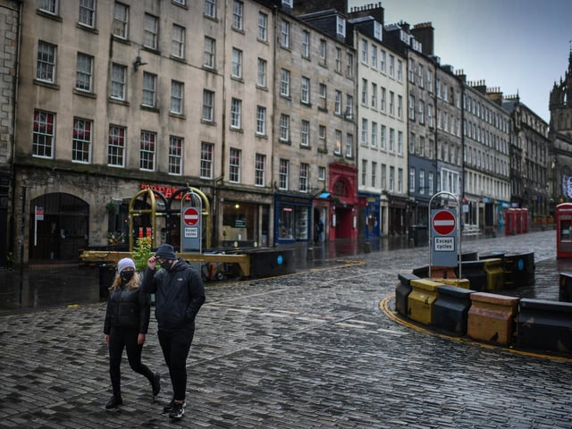 Members of the public walk through a deserted Edinburgh City Centre on January 4, 2021 in Edinburgh, Scotland.