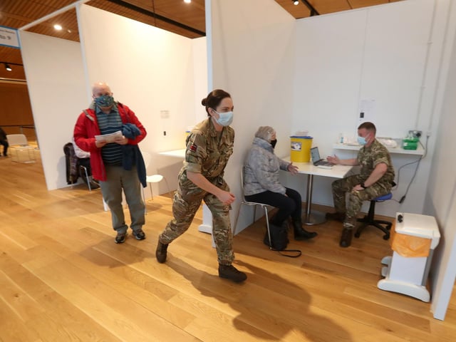 James Logan (left) and Sylvia Campbell (right) receive an injection of a coronavirus vaccine from military personnel.