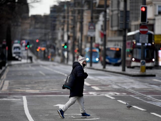 Members of the public walk through a deserted Edinburgh City Centre