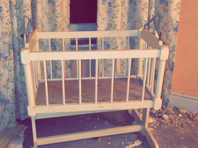 An empty cot stands deserted in one of the bedrooms.