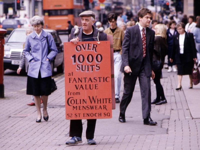 A man wearing a sandwich board advertising suits from Colin White Menswear walks through the city centre Glasgow, August 1990.
